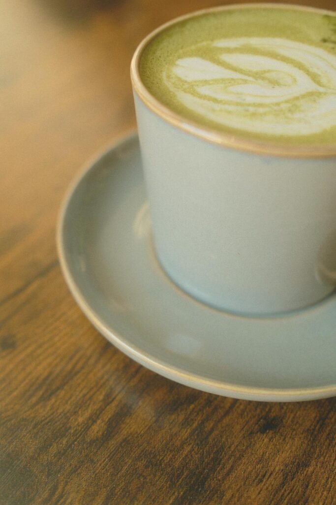 Tasse en céramique de matcha latte avec latte art, posée sur une soucoupe en bois